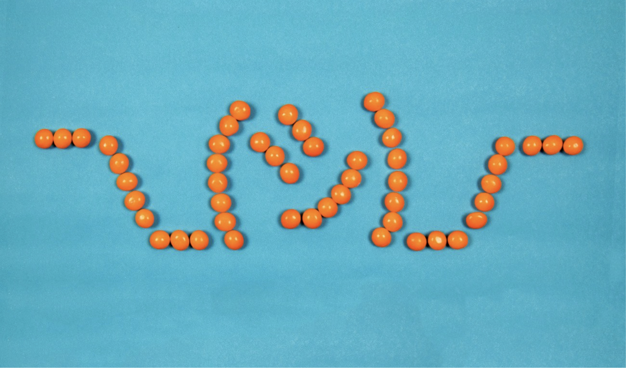 Orange skittles in the shape of the IDK emoji 